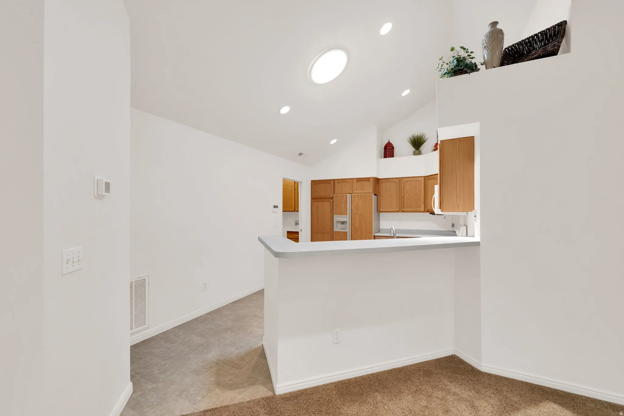 Kitchen with light wood cabinetry, white countertops, and a breakfast bar