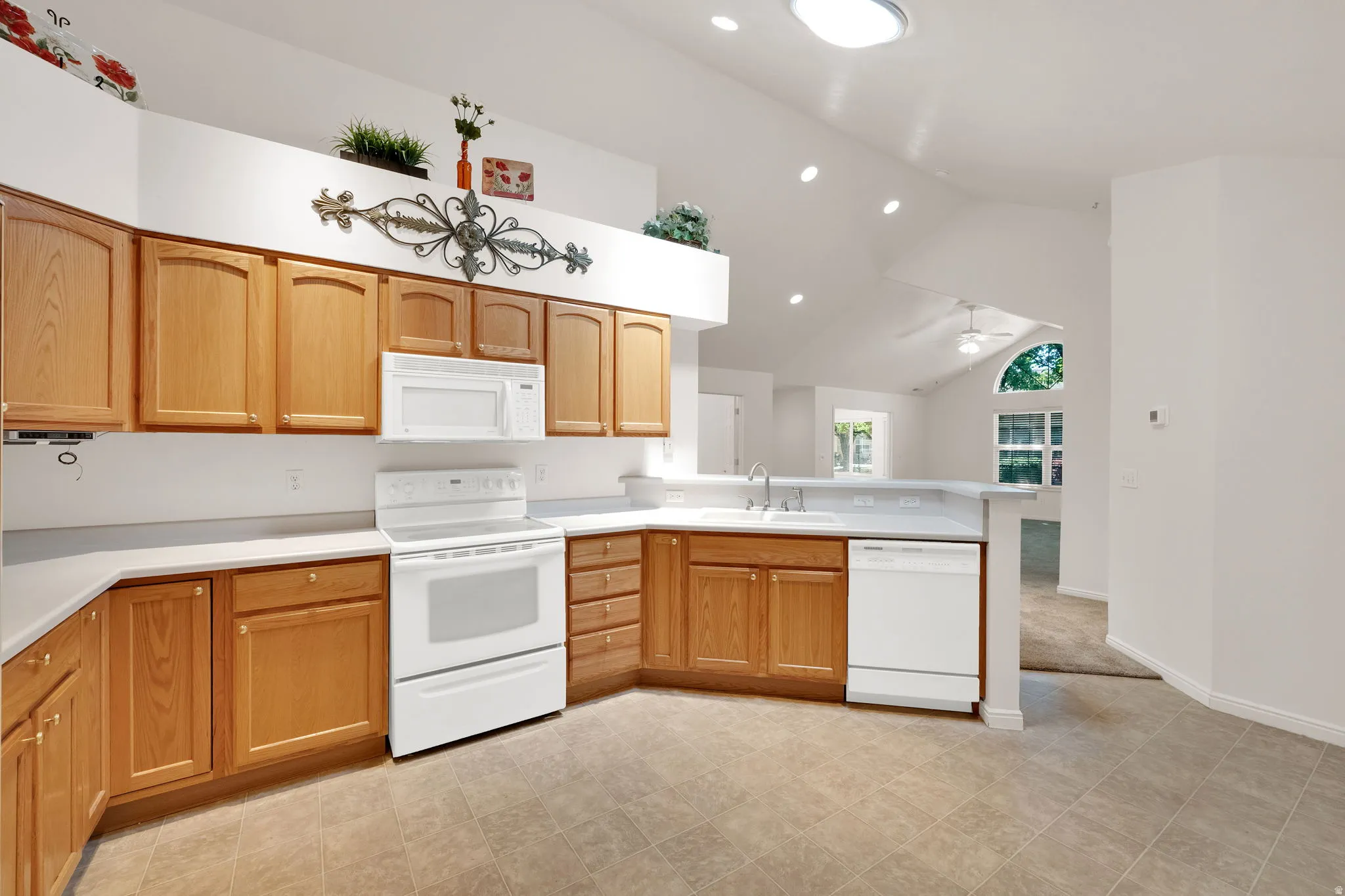 Kitchen featuring light wood cabinetry, white countertops, and white appliances including an oven/range, microwave, and dishwasher
