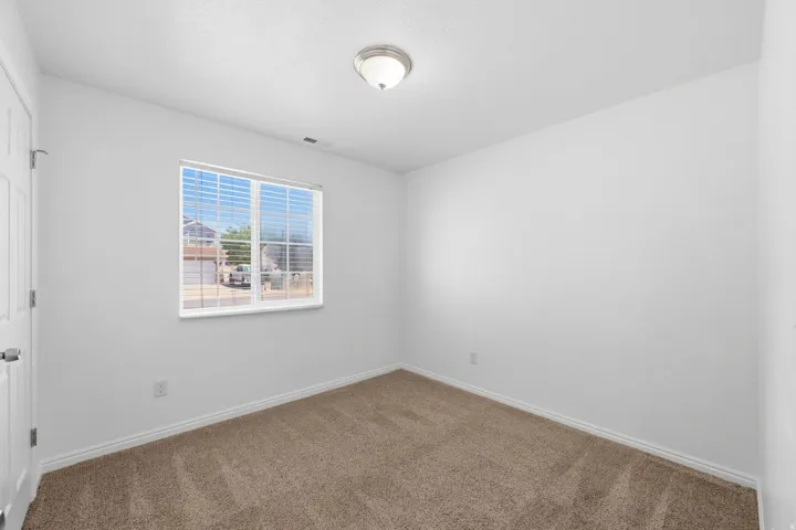 Bedroom 2Carpeted room with white walls, a single window featuring horizontal blinds, white baseboards, and a semi-flush mount ceiling light fixture