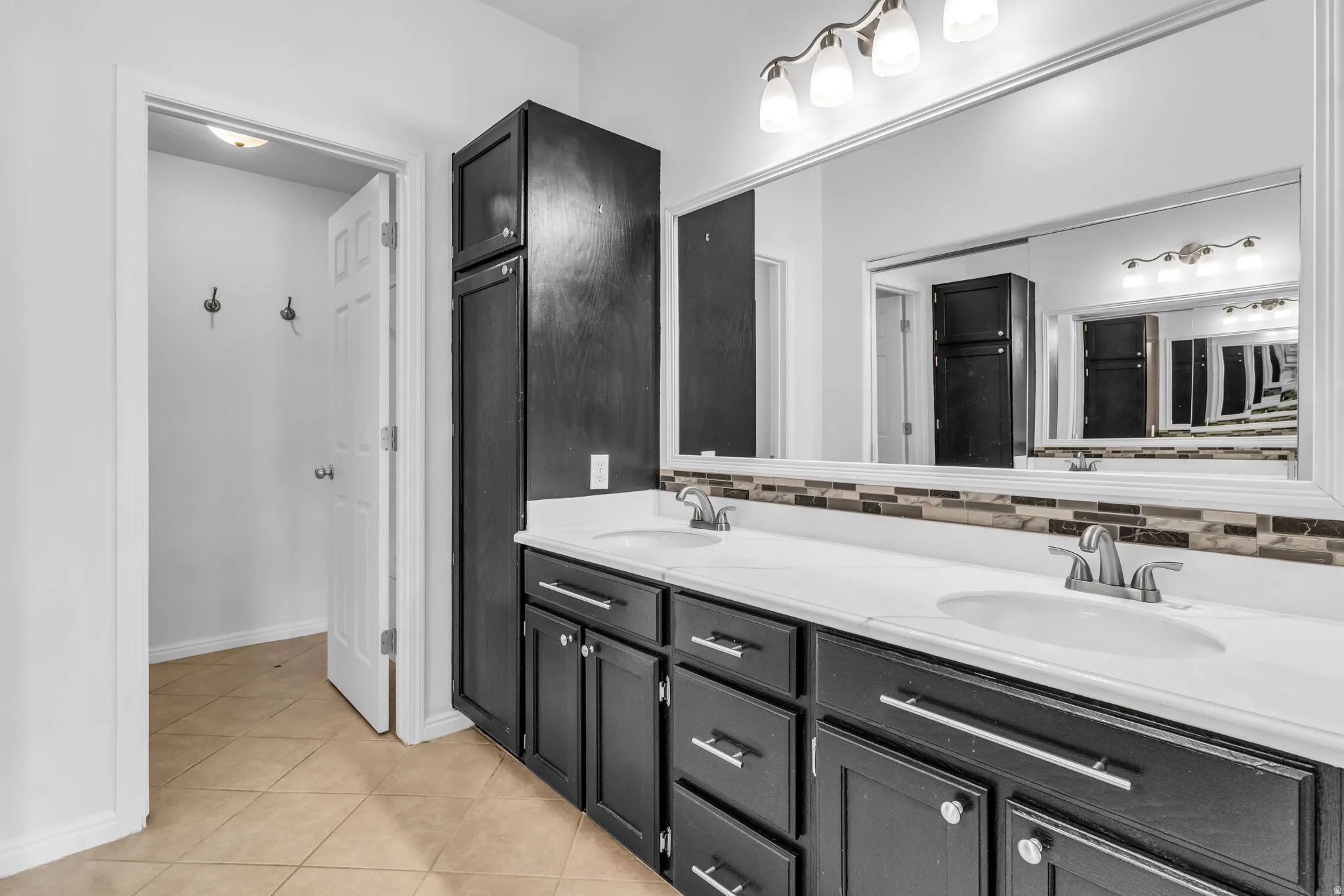 Bathroom featuring a dual vanity with dark wood-finish cabinetry, white countertops, and brushed nickel fixtures