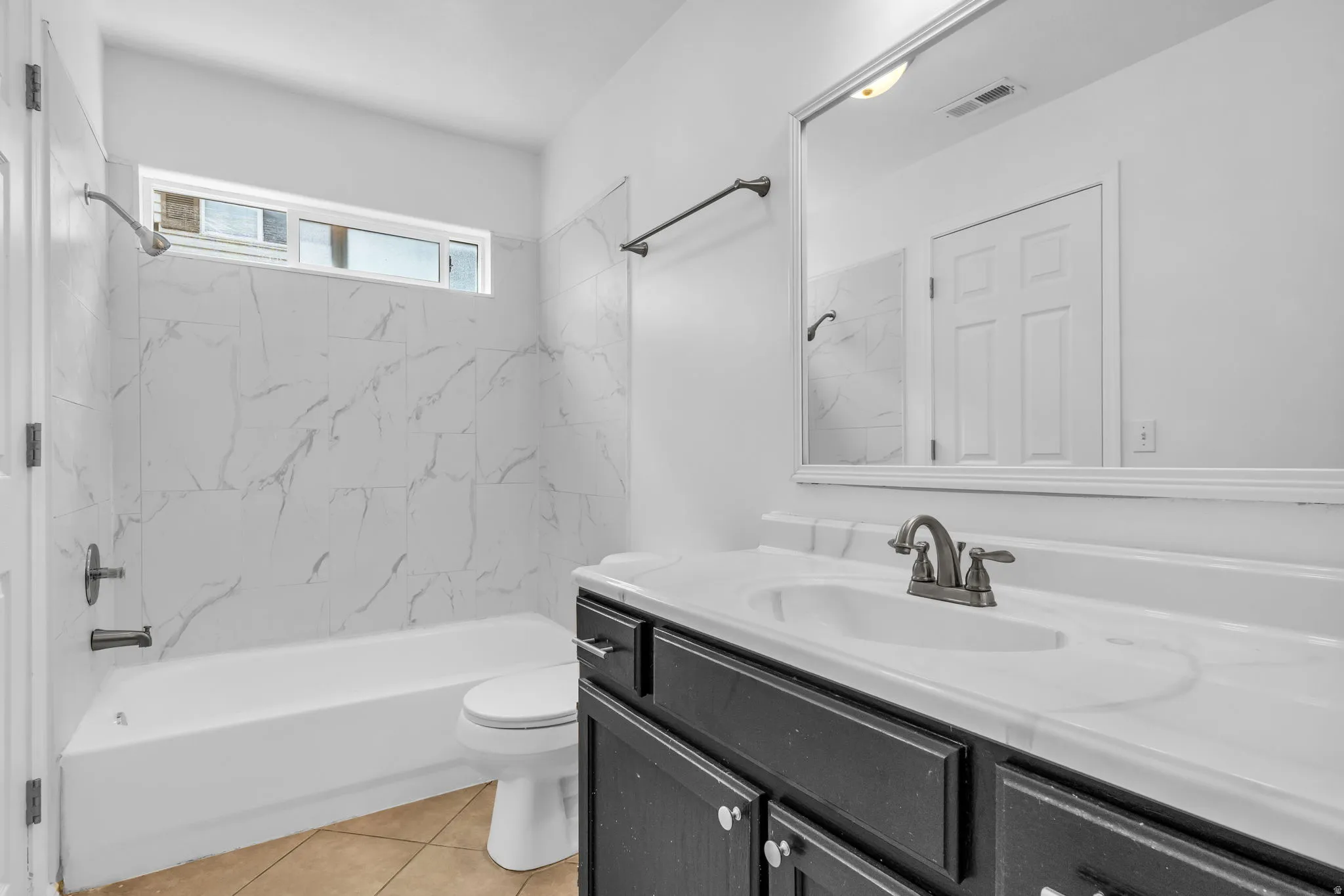 Bathroom featuring a white bathtub, toilet, and vanity with a white countertop and integrated sink