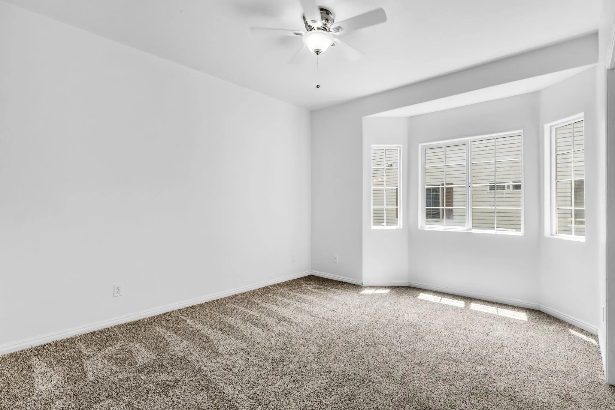 Bedroom featuring plush carpeting, a ceiling fan with light fixture, and a bay window with multiple panes and horizontal blinds