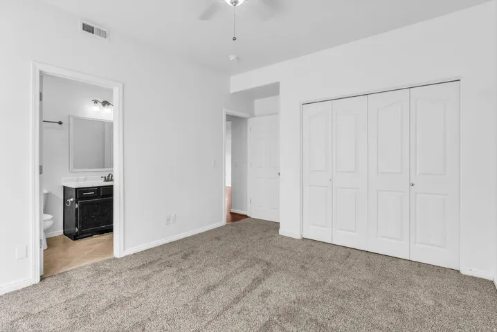 Spacious room featuring neutral carpeting, white walls, and a ceiling fan with integrated lighting