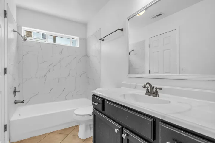 Bathroom featuring a white bathtub, toilet, and vanity with a white countertop and integrated sink