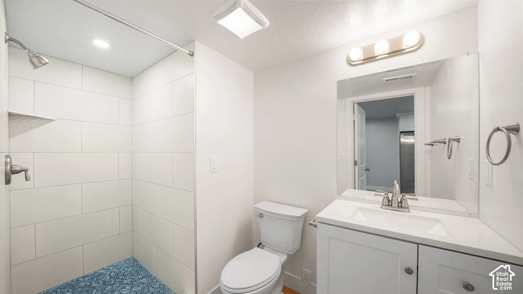 ADU Main Bathroom-2 of 2 Bathrooms-  features white tiled shower with built-in shelving, white vanity with integrated sink, contemporary vanity lighting, and wall-mounted mirror