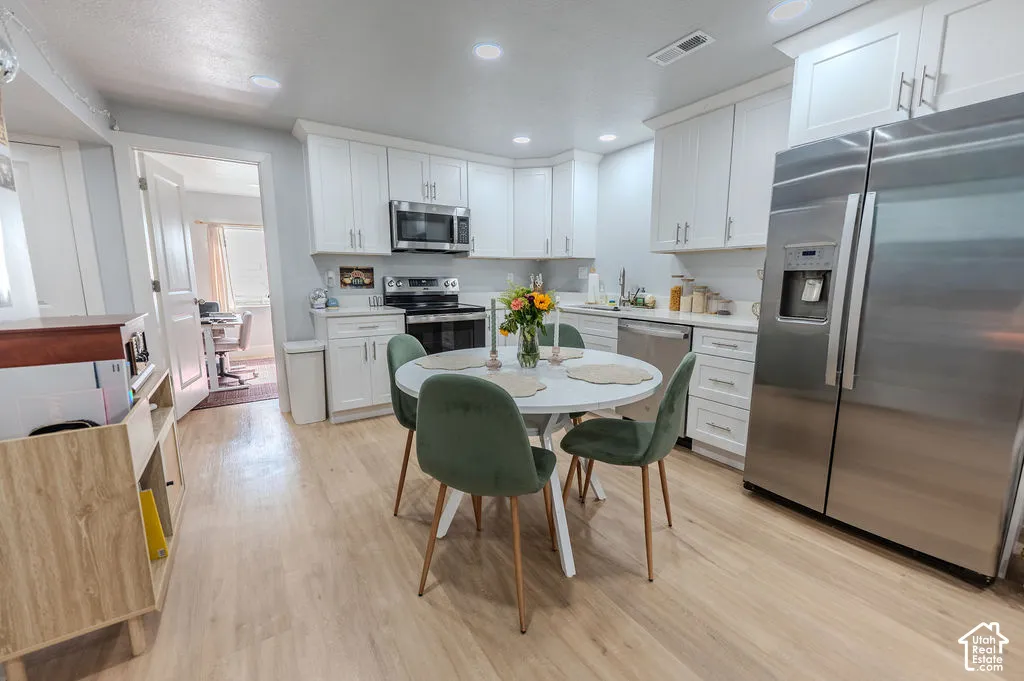 ADU Kitchen featuring white cabinetry, stainless steel appliances, recessed lighting, wood-finish LVP flooring, and a subway tile backsplash