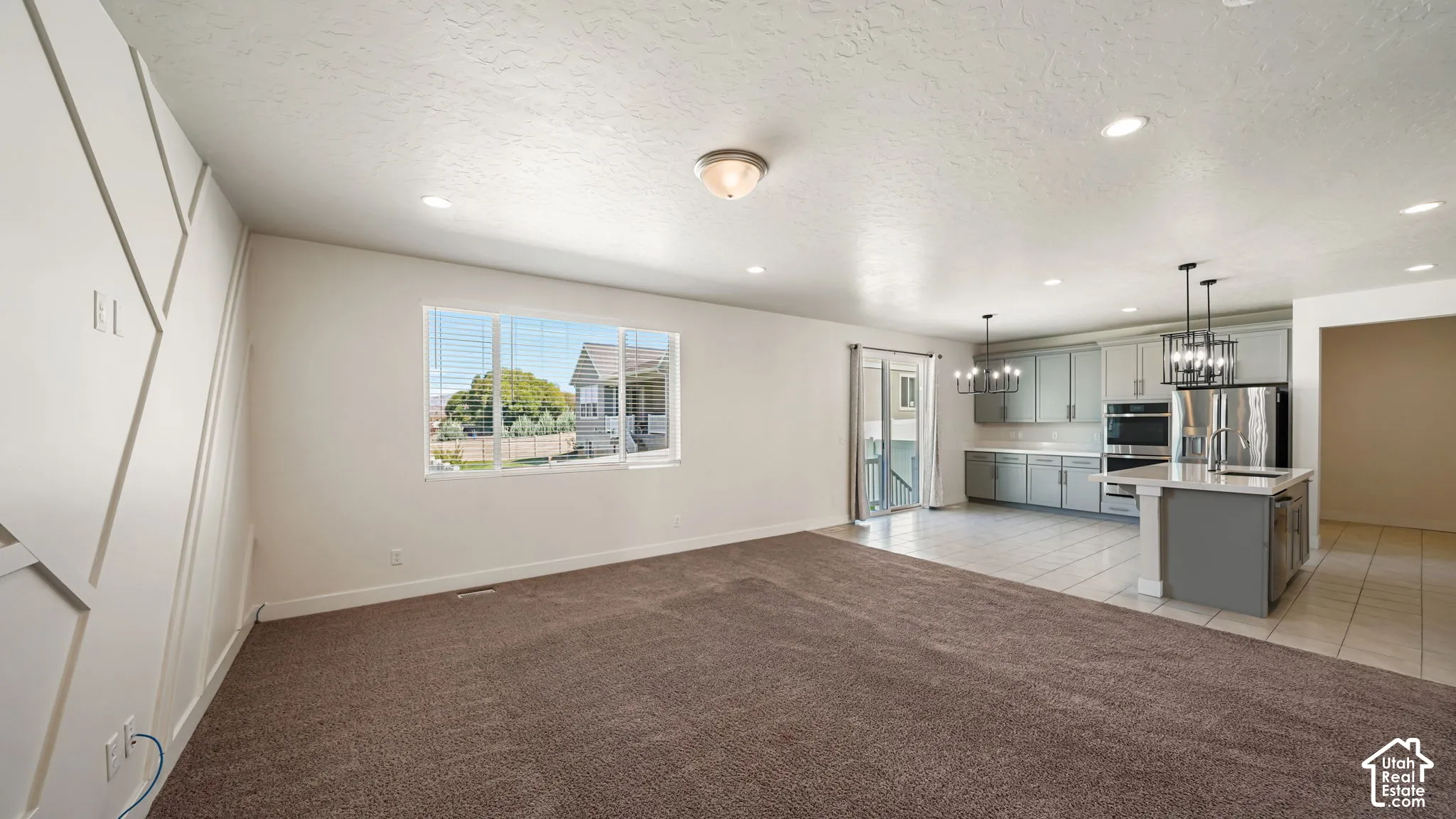 Open-concept Family Room featuring a geometric accent paneled wall, recessed lighting