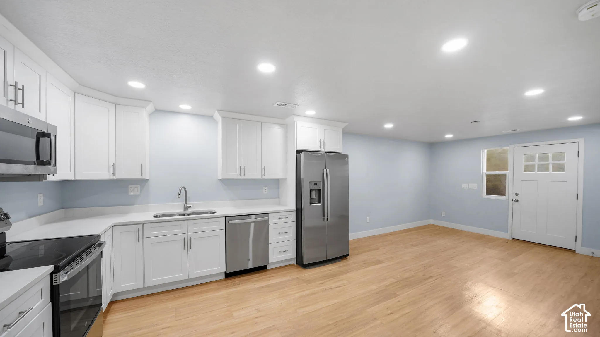 ADU Kitchen featuring white cabinetry, stainless steel appliances, solid surface countertops, and recessed lighting