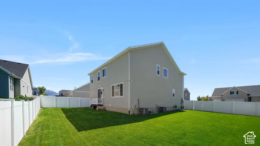 Expansive backyard with a manicured lawn, full privacy fencing, and a built-in rear patio