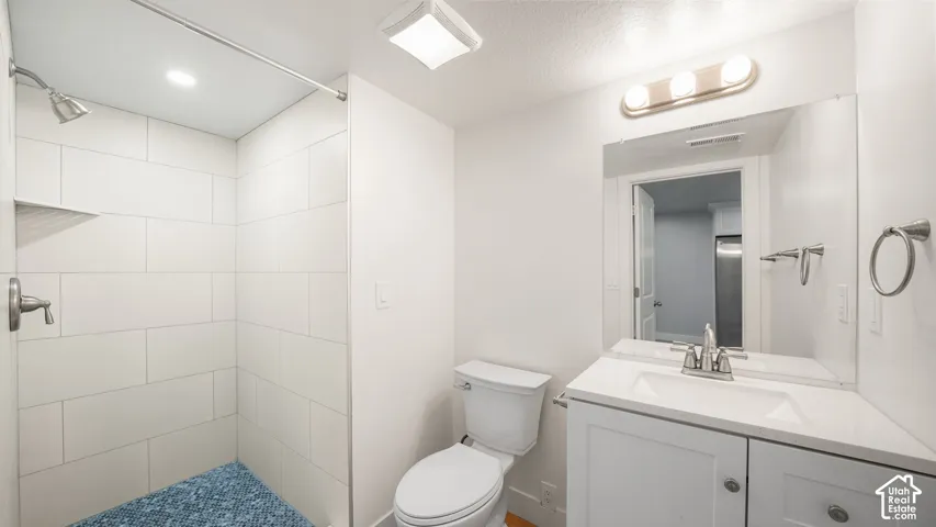ADU Main Bathroom-2 of 2 Bathrooms-  features white tiled shower with built-in shelving, white vanity with integrated sink, contemporary vanity lighting, and wall-mounted mirror