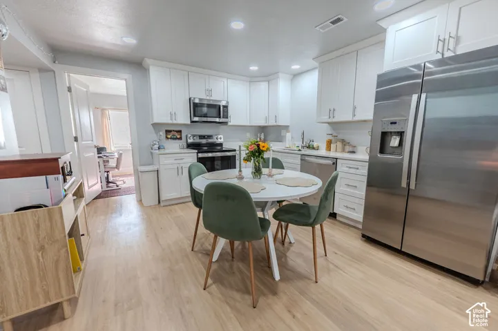 ADU Kitchen featuring white cabinetry, stainless steel appliances, recessed lighting, wood-finish LVP flooring, and a subway tile backsplash