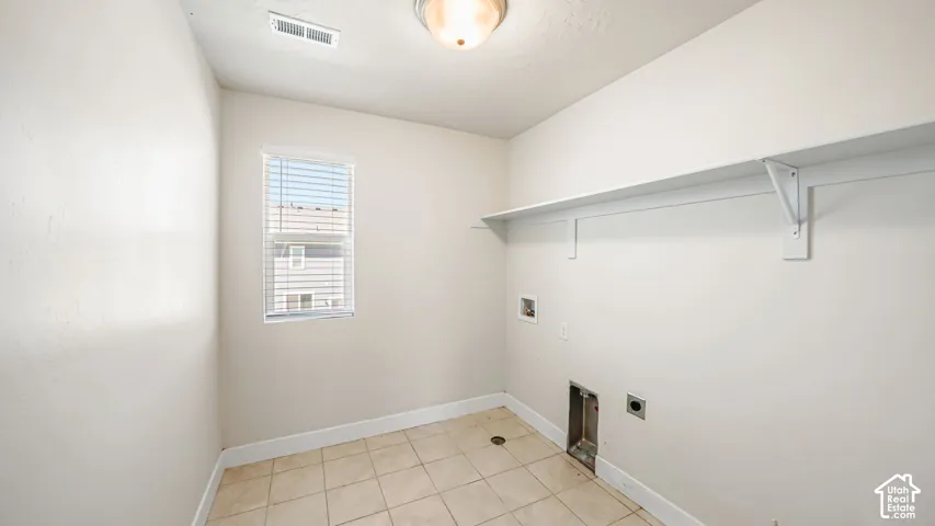Spacious LAUNDRY ROOM conveniently located upstairs near the bedrooms has tiled flooring, overhead shelving