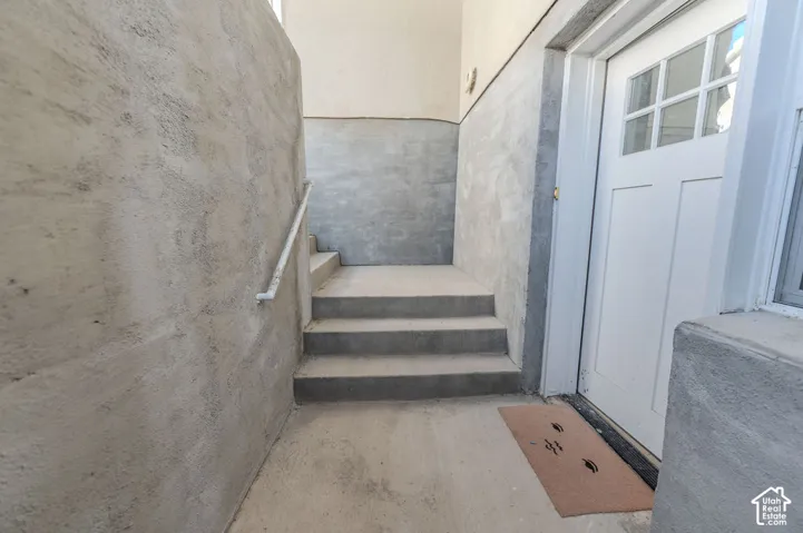 Exterior entryway w/ Landing featuring ULTRA-WIDE concrete steps with a wall-mounted handrail