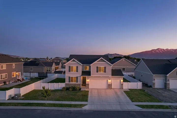 Contemporary two-story residence featuring a three-car garage, stone and siding exterior, and a manicured front lawn