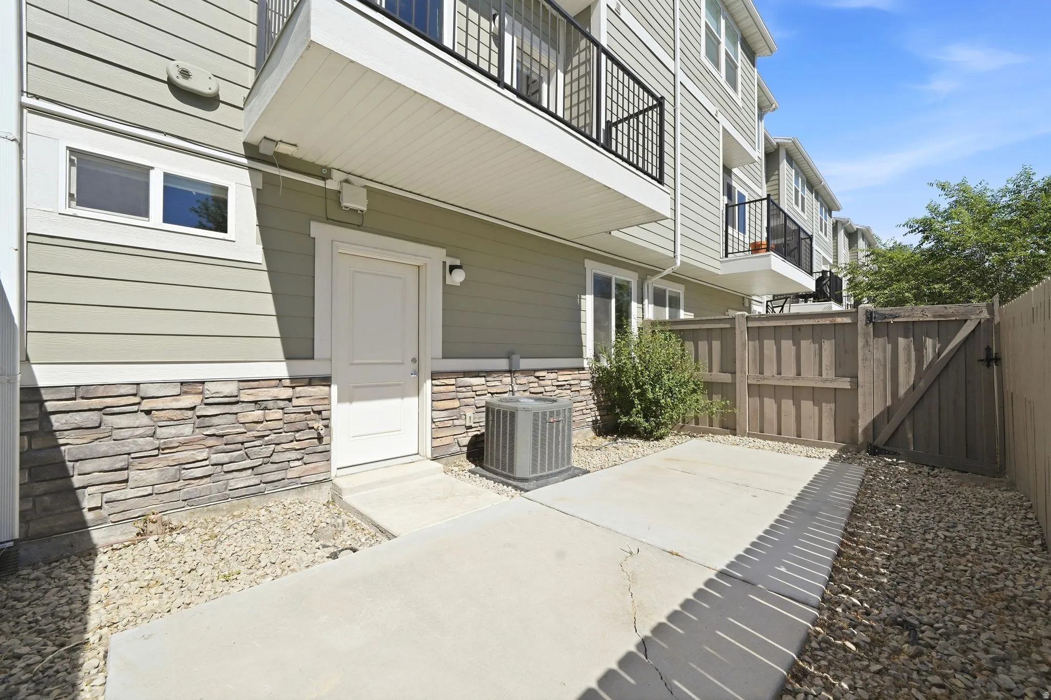 Private patio area featuring a concrete surface, gravel landscaping, and a wooden privacy fence