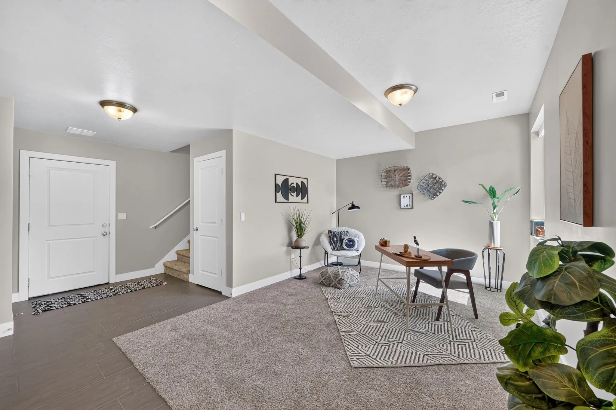 Spacious room featuring neutral paint, overhead lighting, an entryway with tile flooring, and carpeted living space