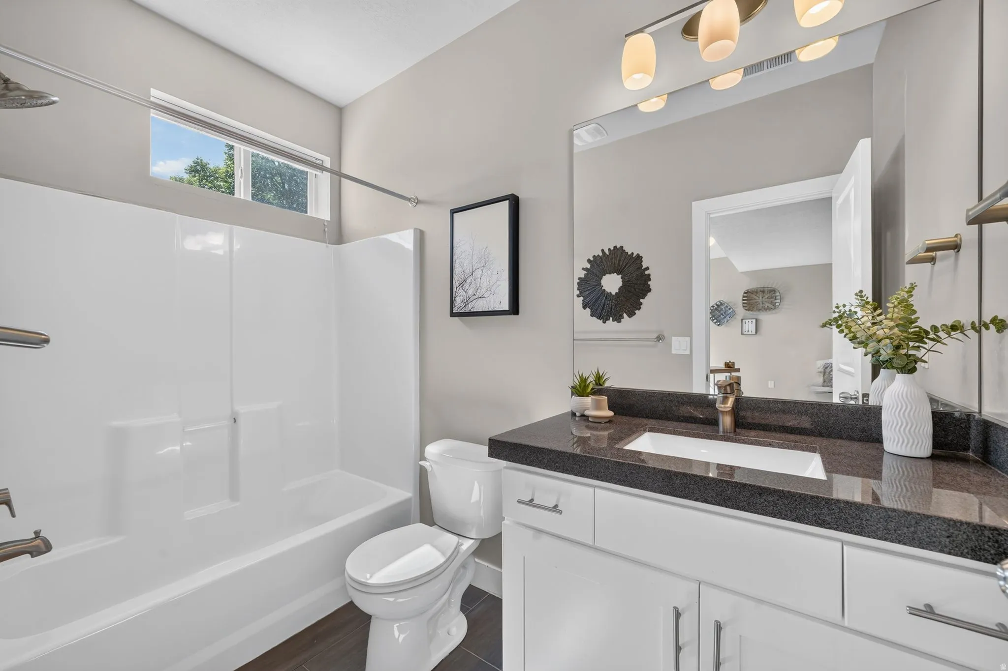 Bathroom featuring a white vanity with dark countertop, an integrated sink, and bronze-finish faucet