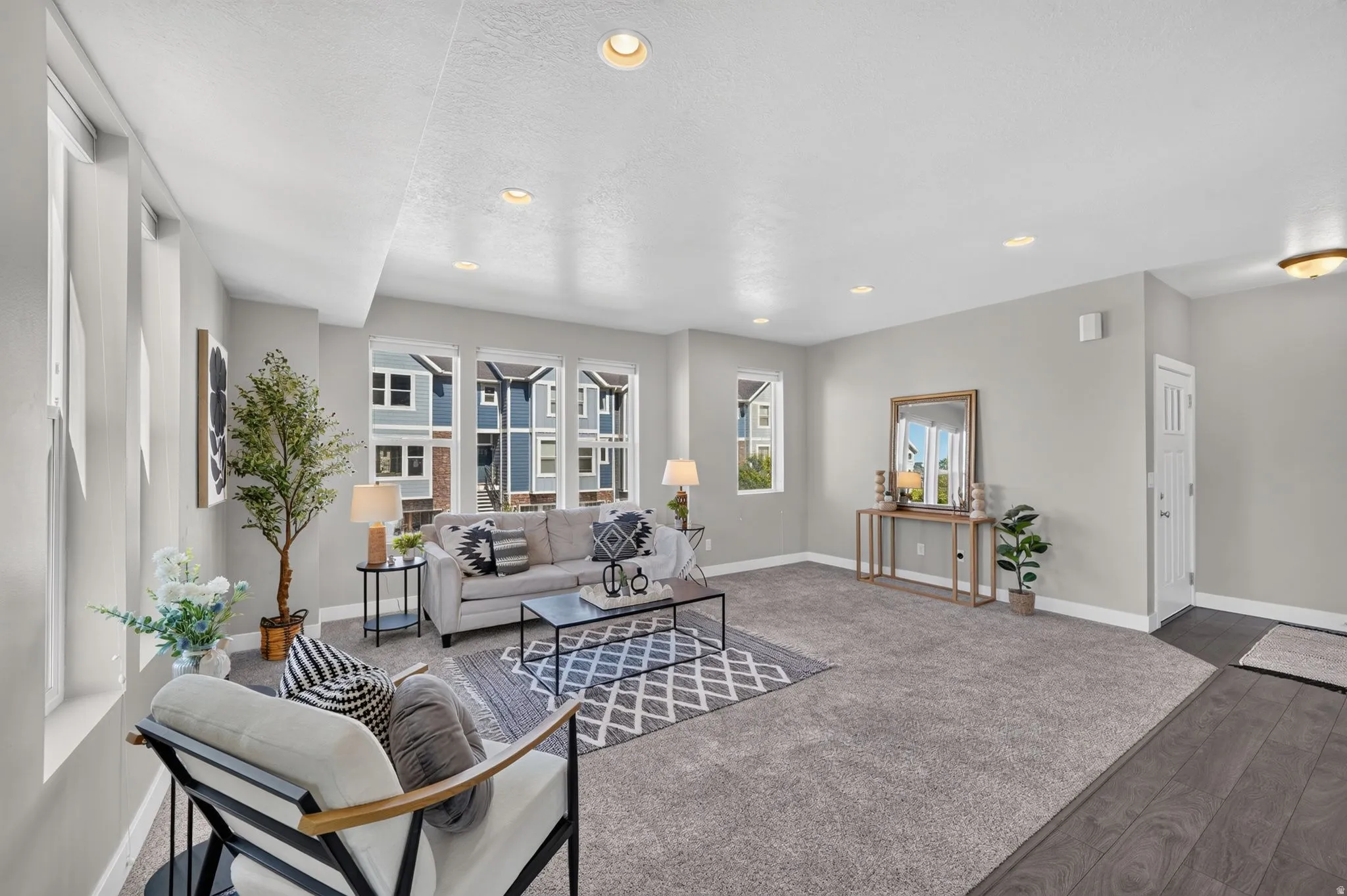 Spacious living area featuring light gray walls, recessed lighting, and large windows