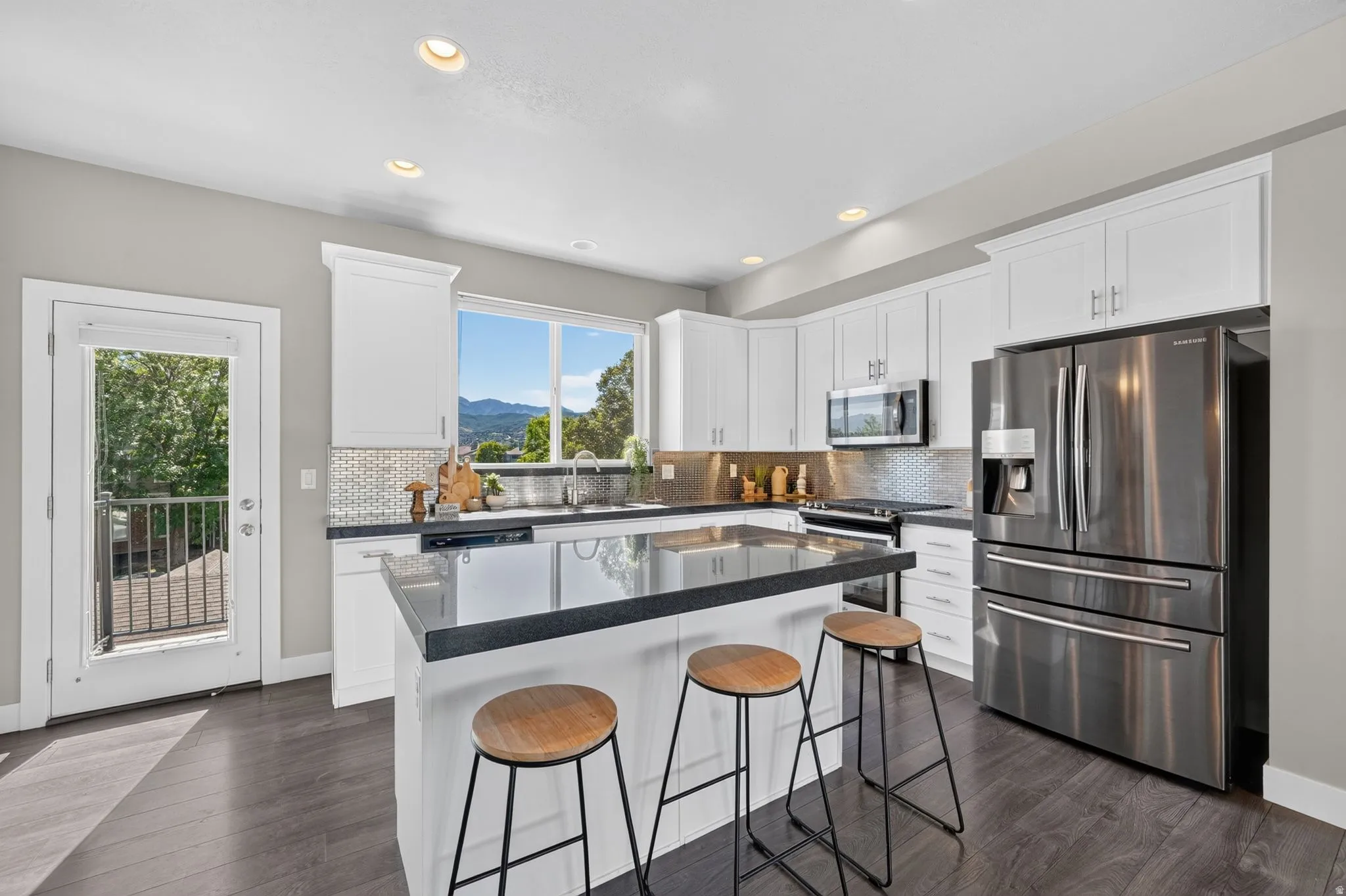 Contemporary kitchen featuring white cabinetry, dark countertops, and stainless steel appliances