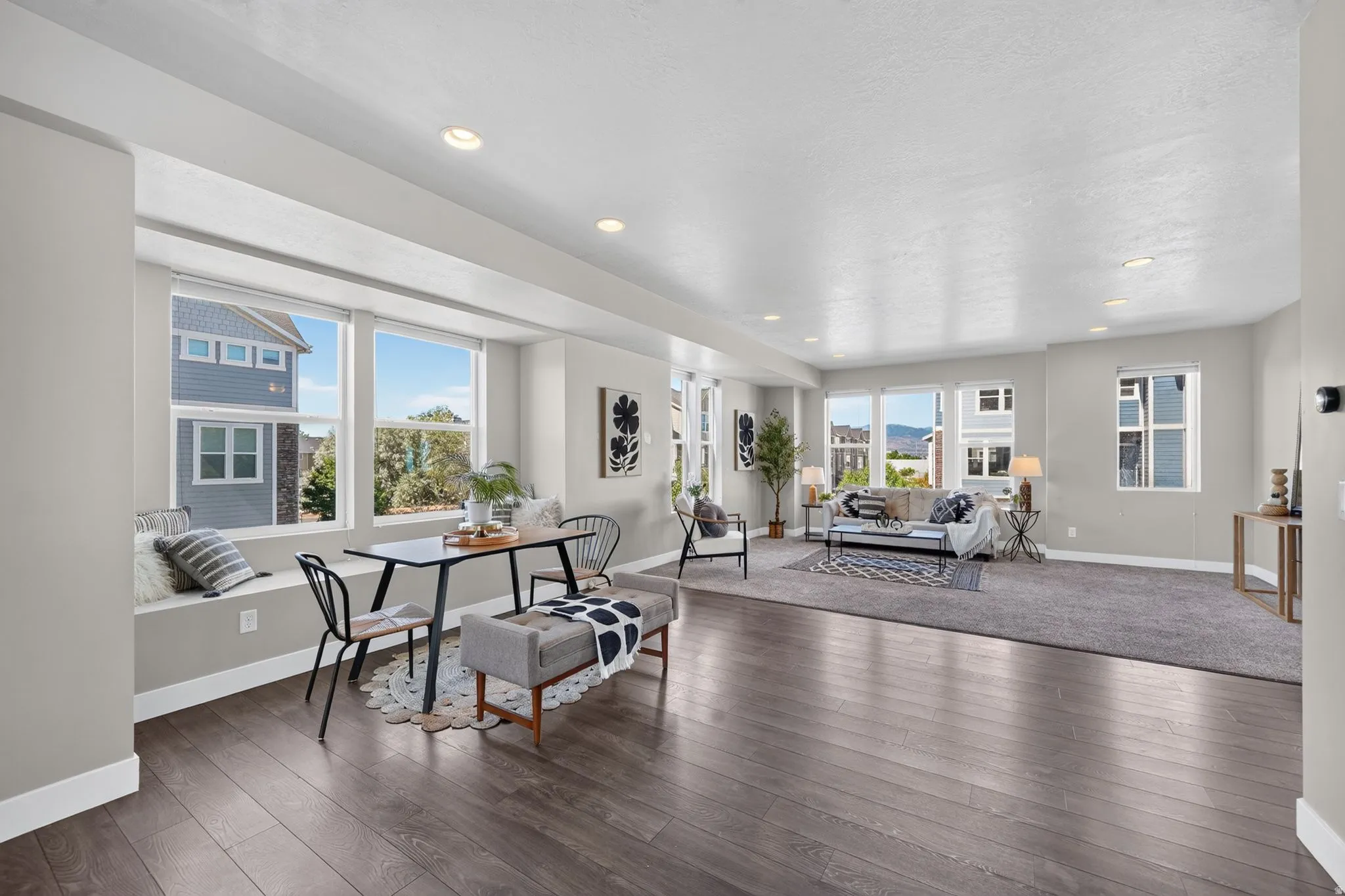 Open-concept living area featuring wood-finish flooring, a built-in window bench, recessed lighting, and expansive windows