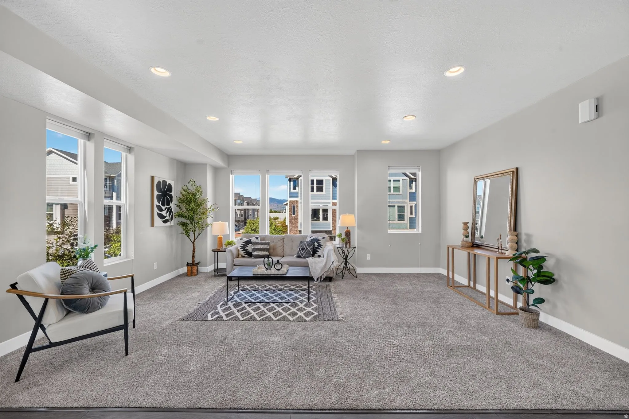 Spacious living area featuring light gray walls, recessed lighting, and ample natural light from multiple windows