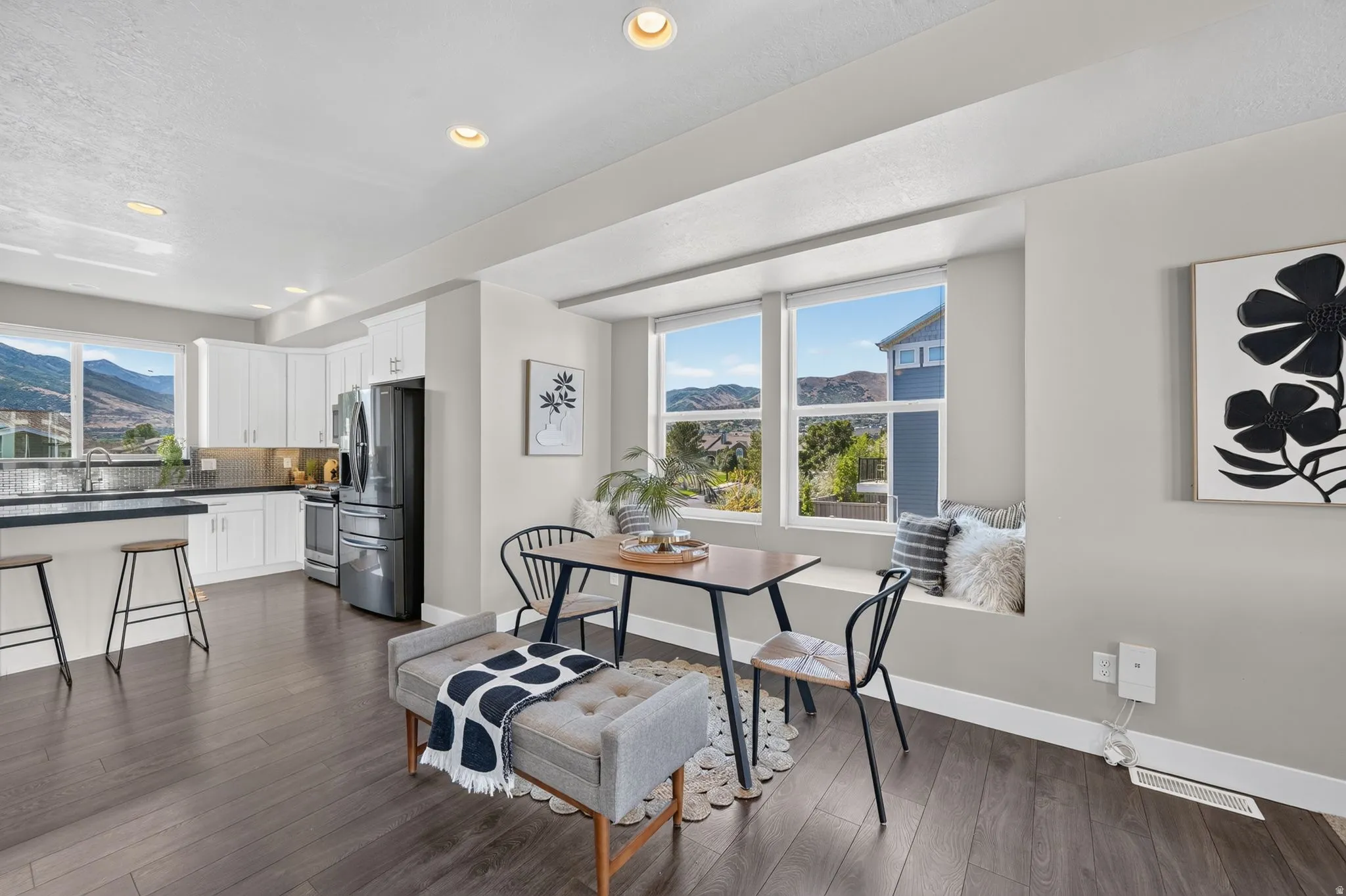 Kitchen and dining area featuring dark wood-finish flooring, recessed lighting, and white baseboards