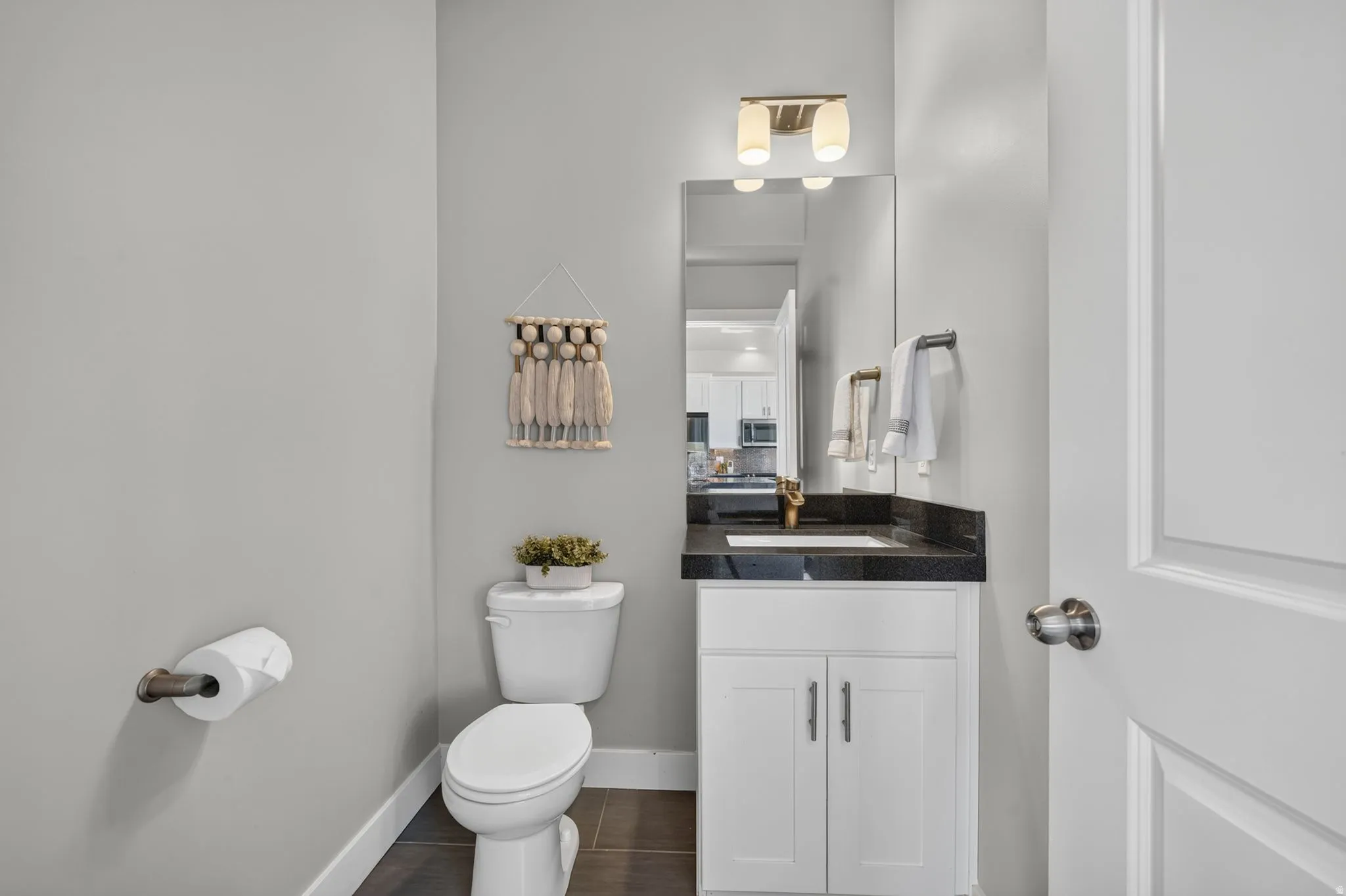 Powder room featuring a white single vanity with dark countertop, undermount sink, and wall-mounted light fixture