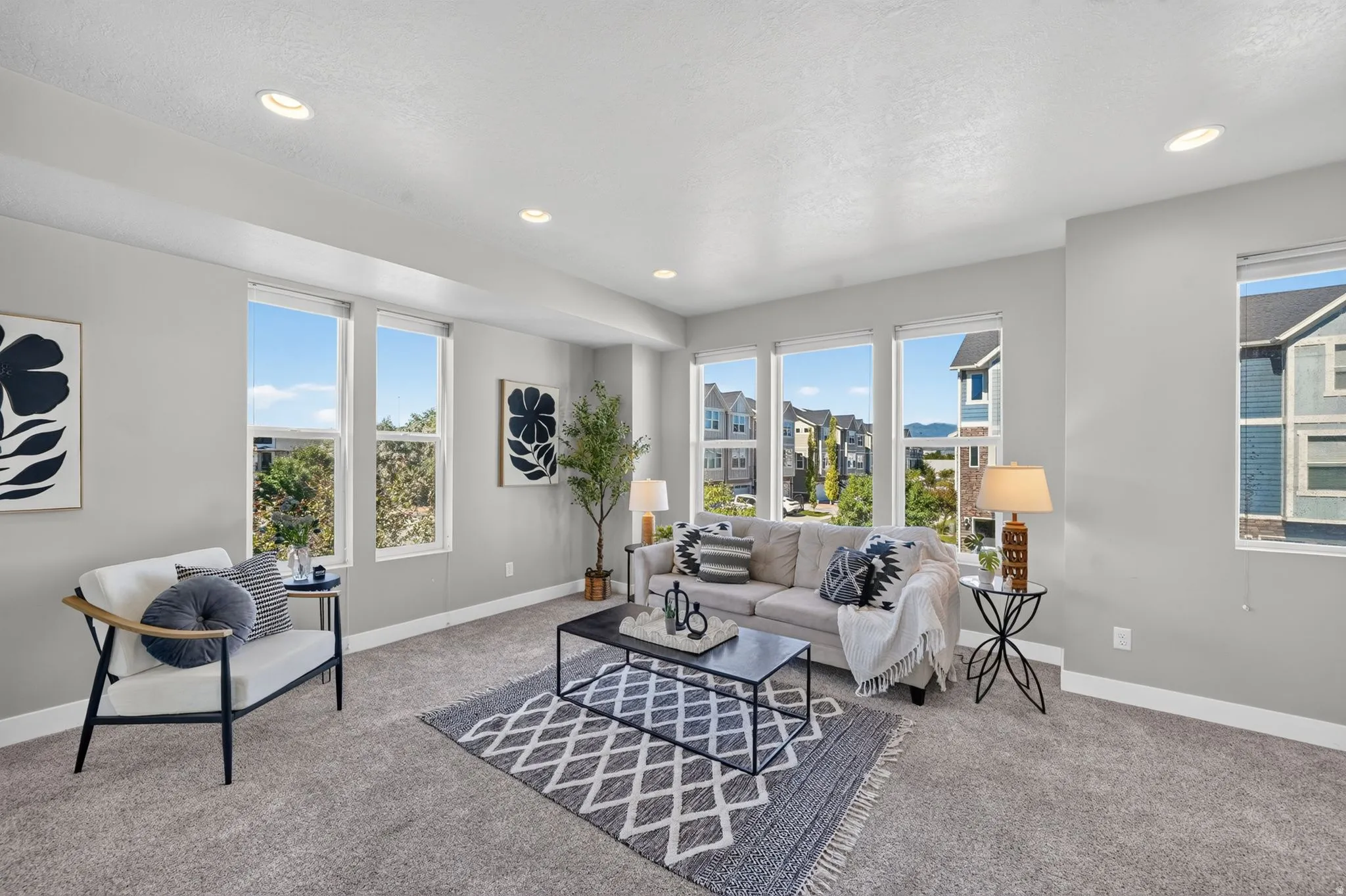 Spacious living area featuring light gray walls and plush gray carpeting
