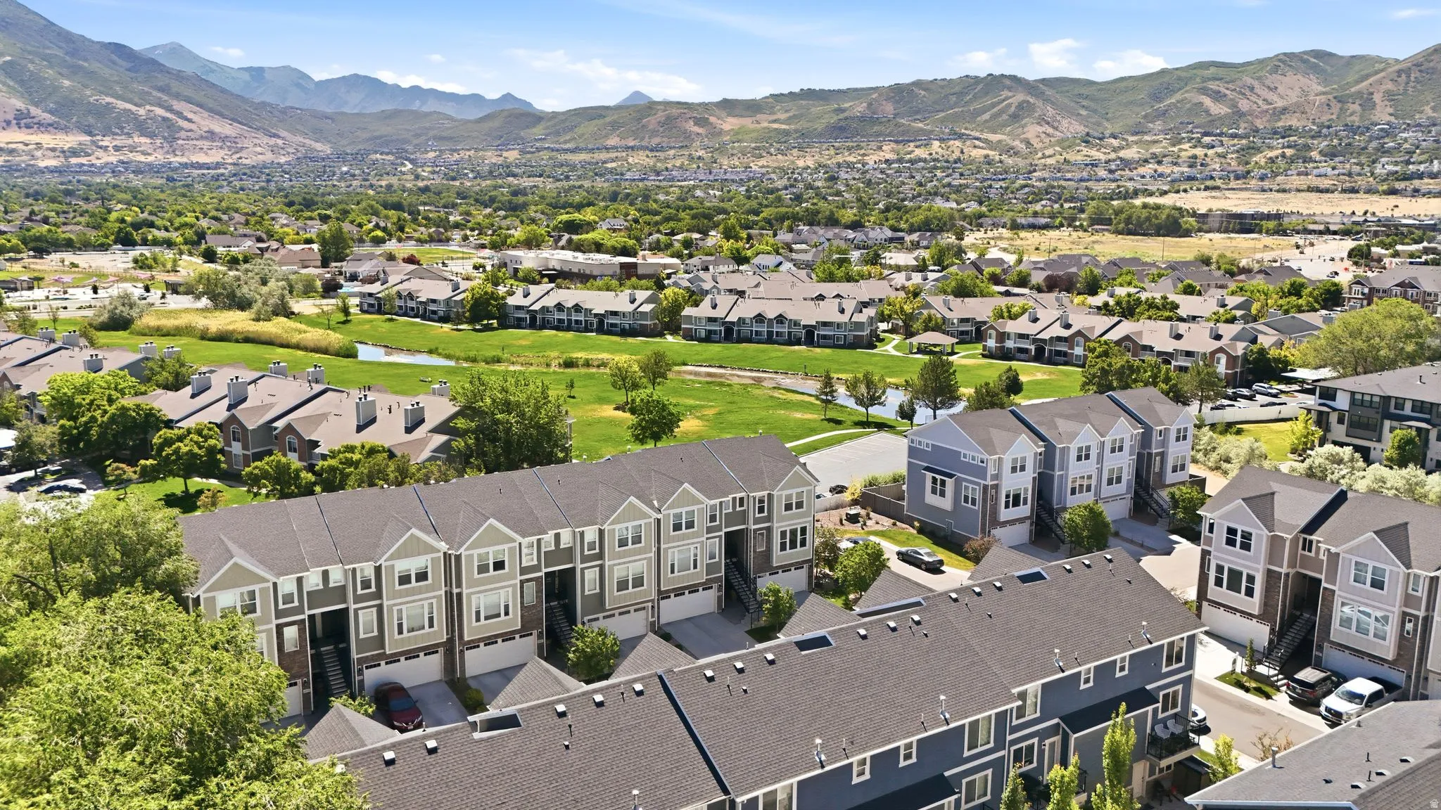 Aerial perspective showcasing a community of multi-story townhomes with pitched roofs and individual garages