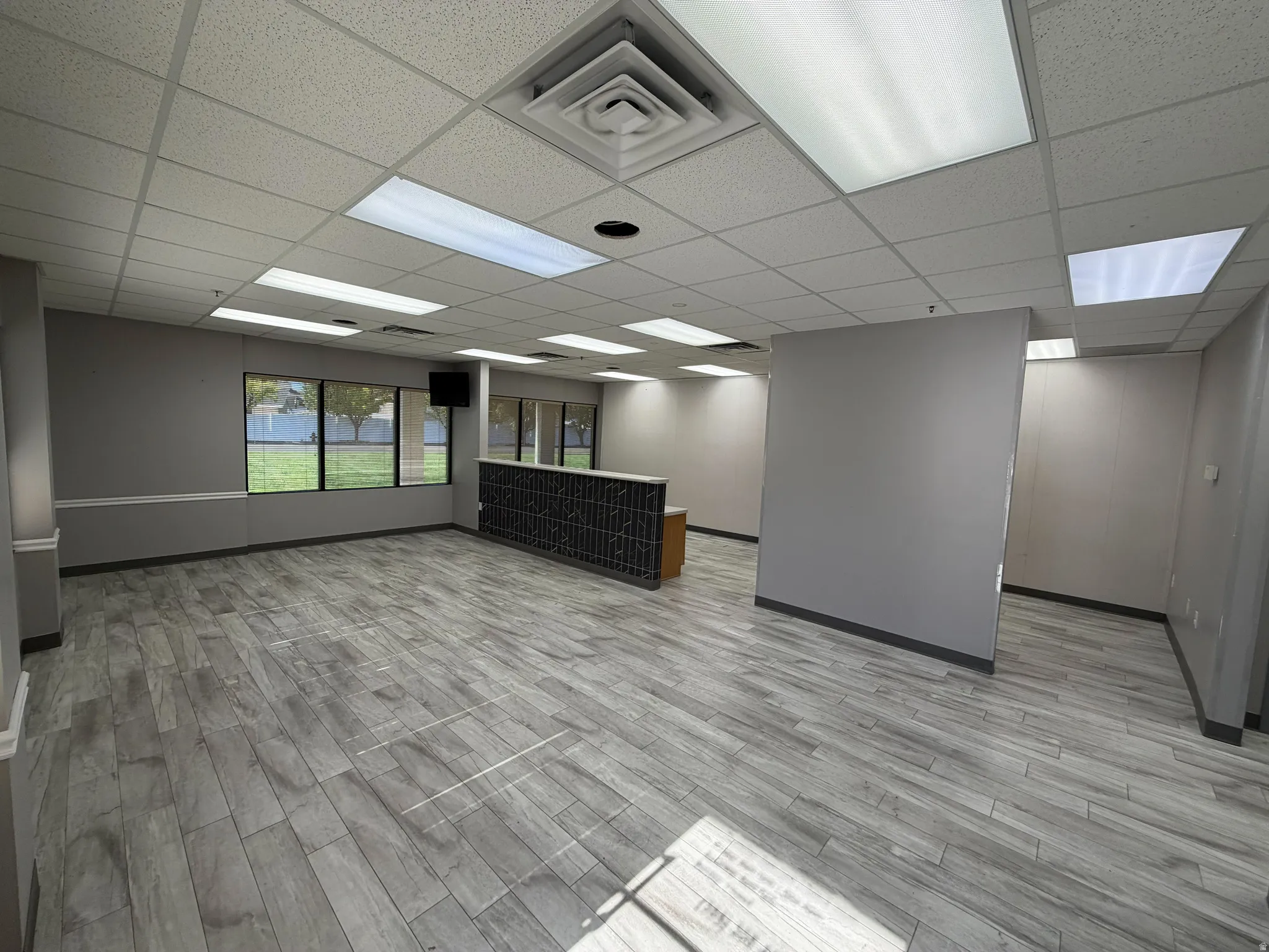 Open commercial space featuring wood-finish flooring, recessed lighting, and large windows