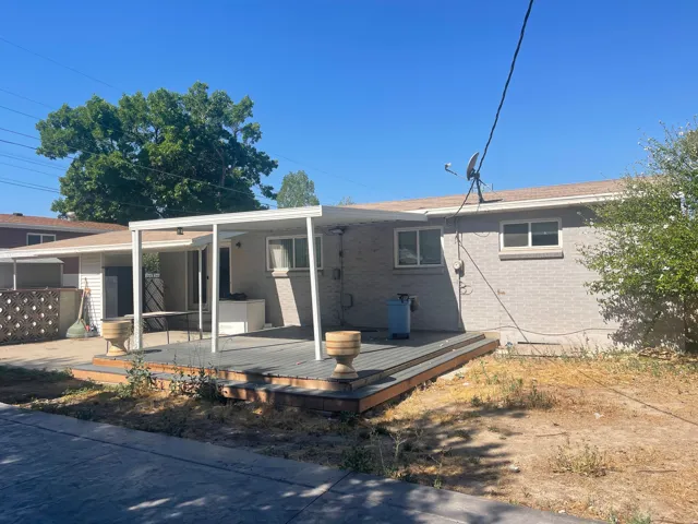 Expansive rear deck with covered patio, durable brick exterior, and multiple windows