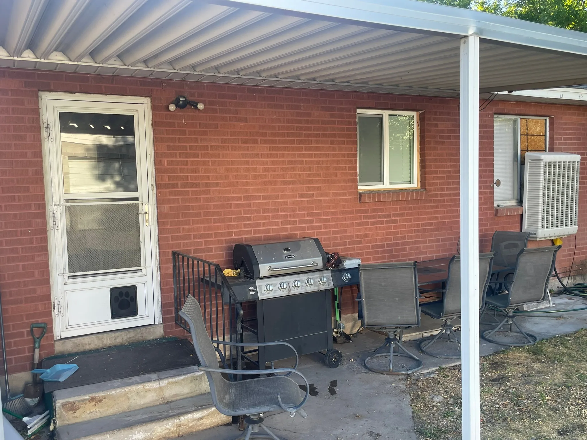 Covered patio featuring a solid brick exterior, white-framed windows, and a security light fixture