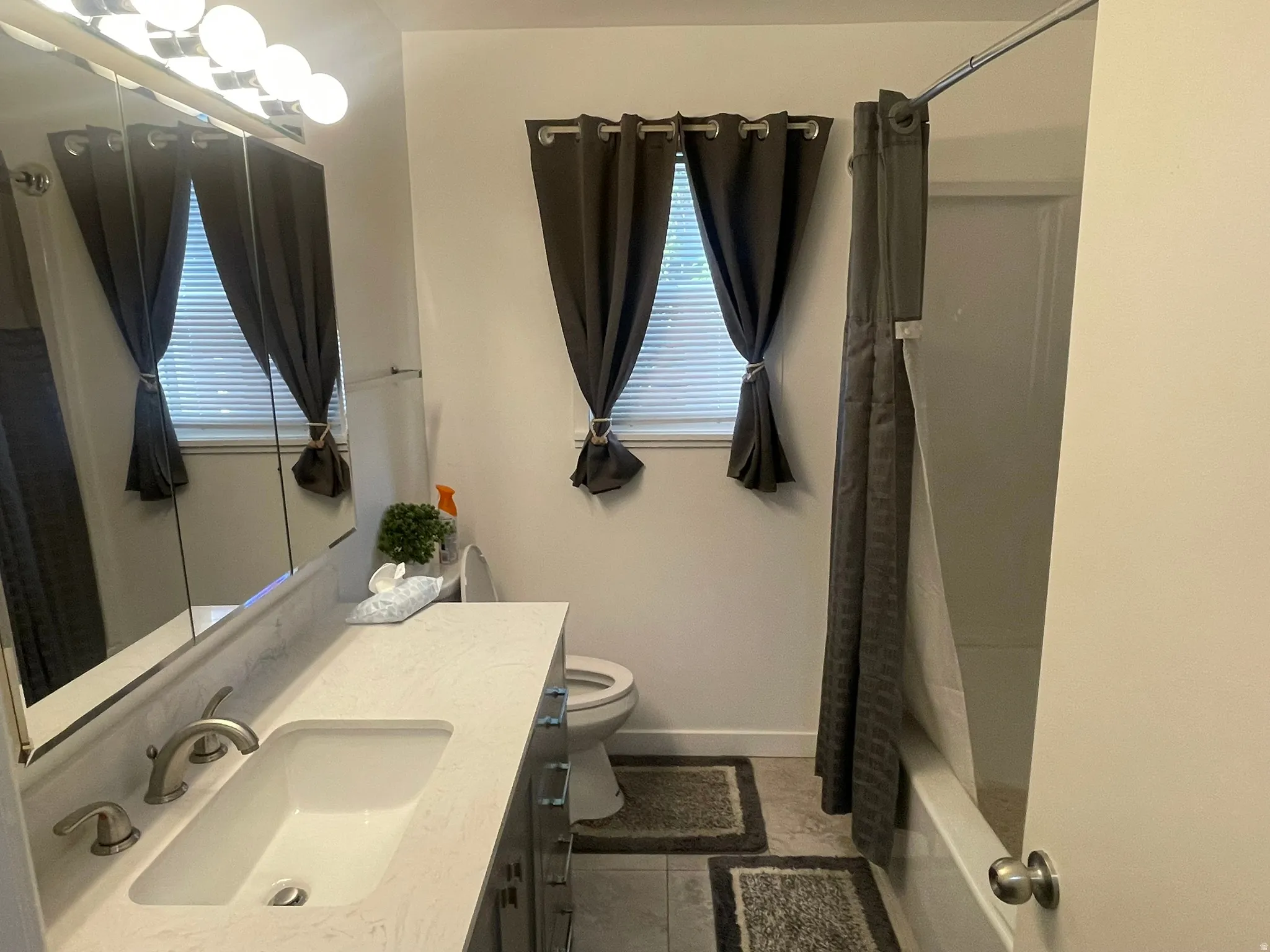 Bathroom featuring a single vanity with an integrated sink, brushed nickel faucet, and a large mirrored medicine cabinet