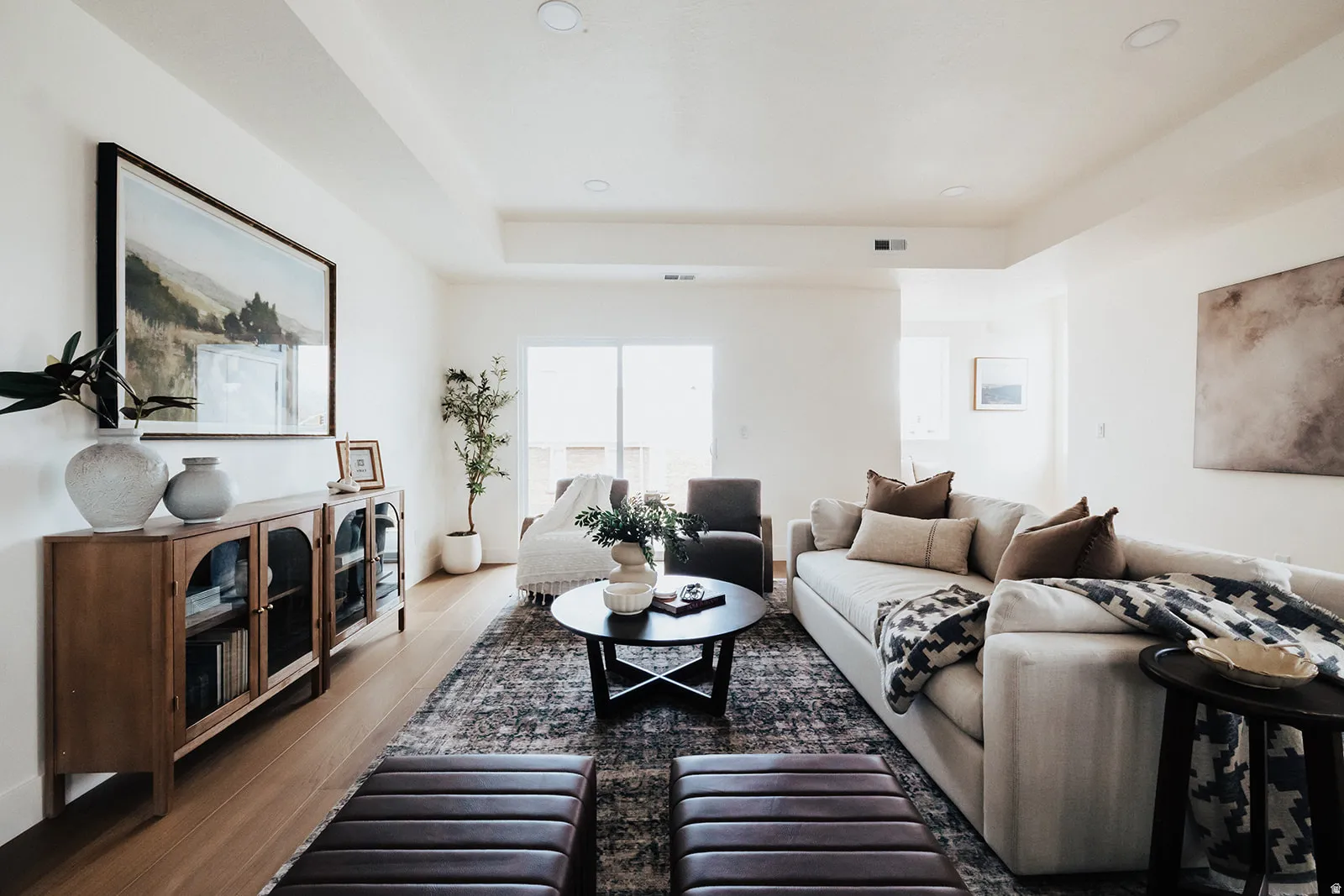 Expansive living area featuring light wood-finish flooring, recessed lighting, and a neutral color palette