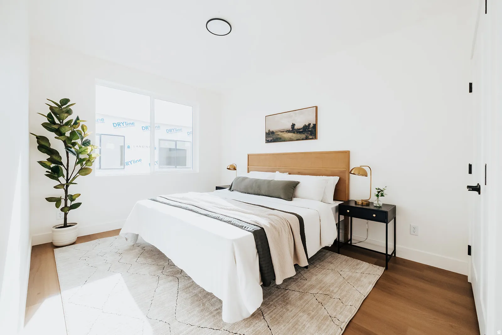 Bedroom featuring light wood-finish flooring, white walls, and a large window