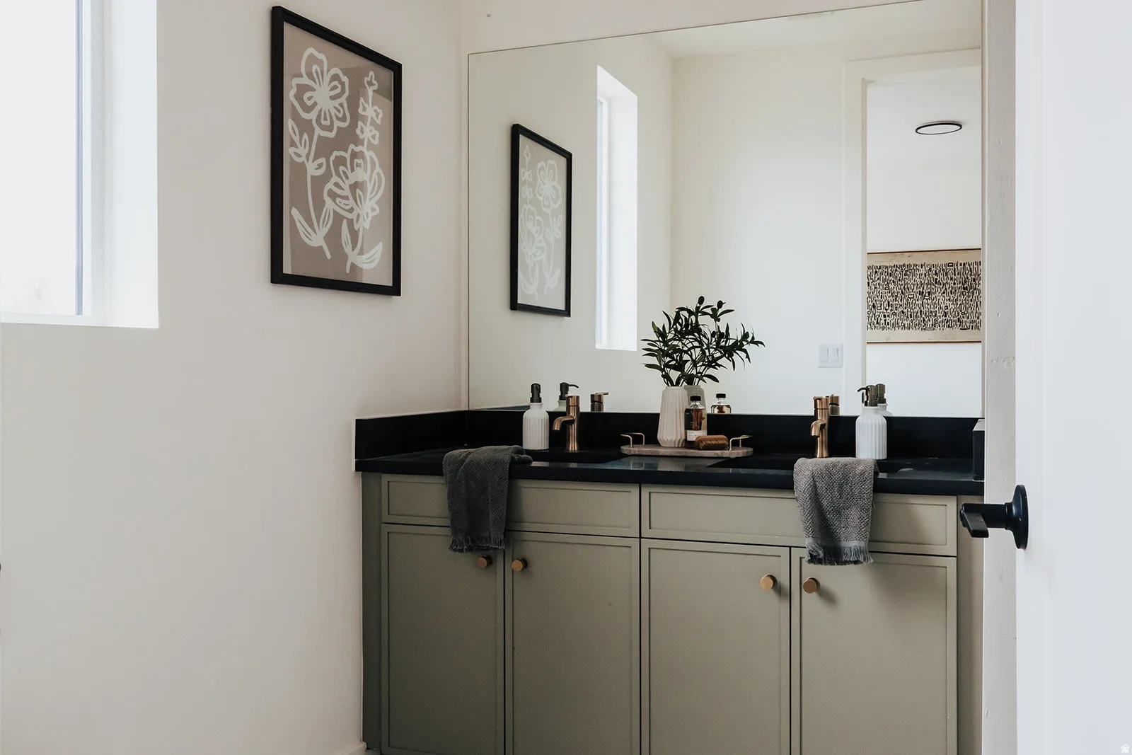 Double vanity featuring a black countertop, dual undermount sinks, and gold-finish faucets