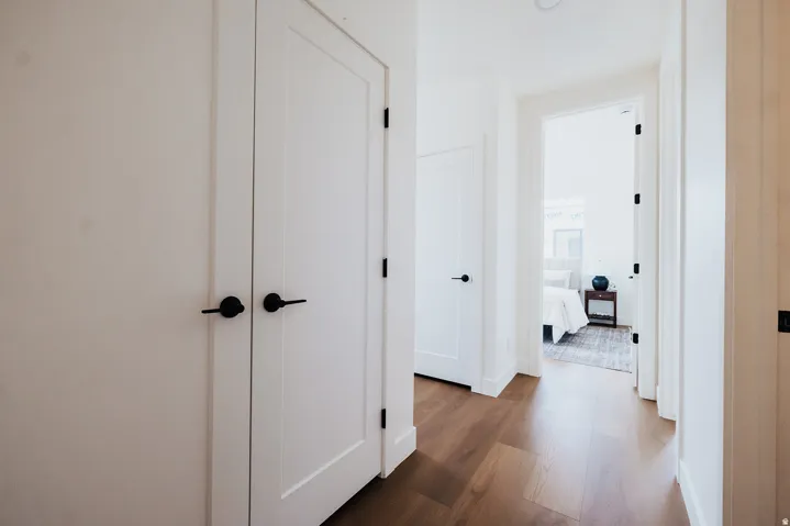Hallway featuring wood-finish flooring, white walls, and bright overhead lighting