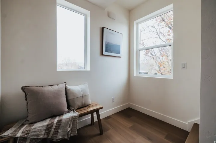 Corner landing featuring two white-framed windows, wood-finish flooring, white baseboards, and neutral wall paint