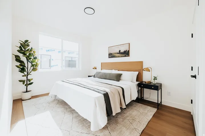 Bedroom featuring light wood-finish flooring, white walls, and a large window