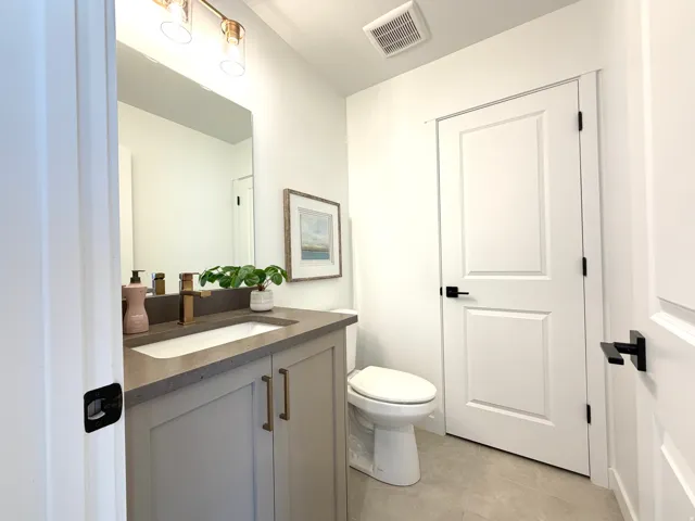 Modern vanity featuring a built-in sink, dark countertop, and gold-finish faucet