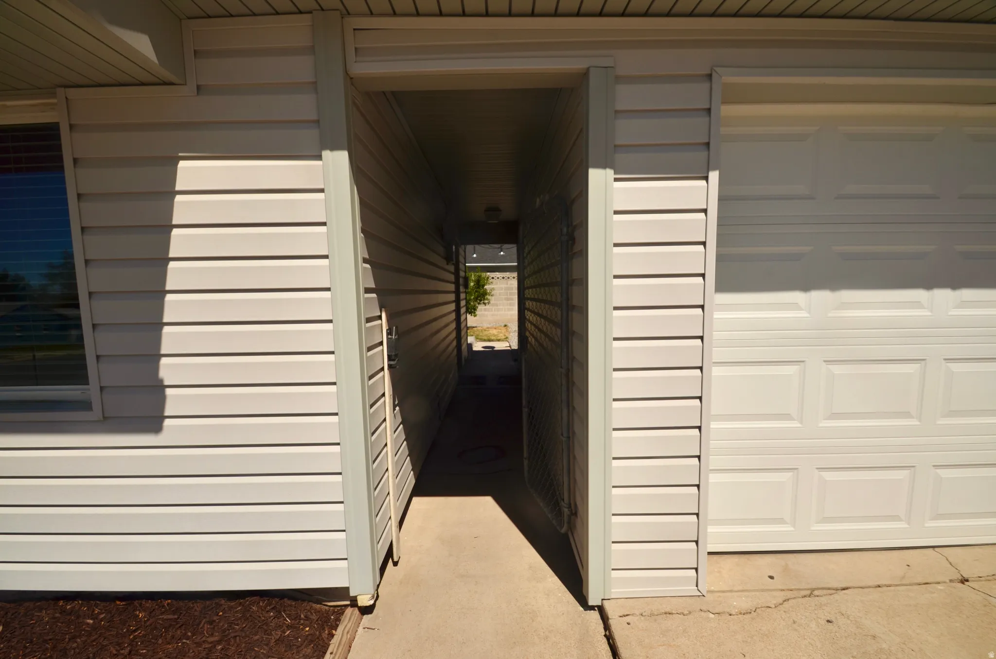 Covered breezeway entry with vinyl siding and concrete walkway