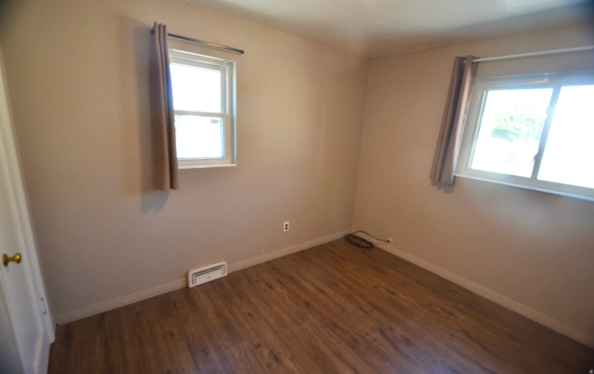 Room featuring wood-finish flooring, two windows, and neutral wall tones