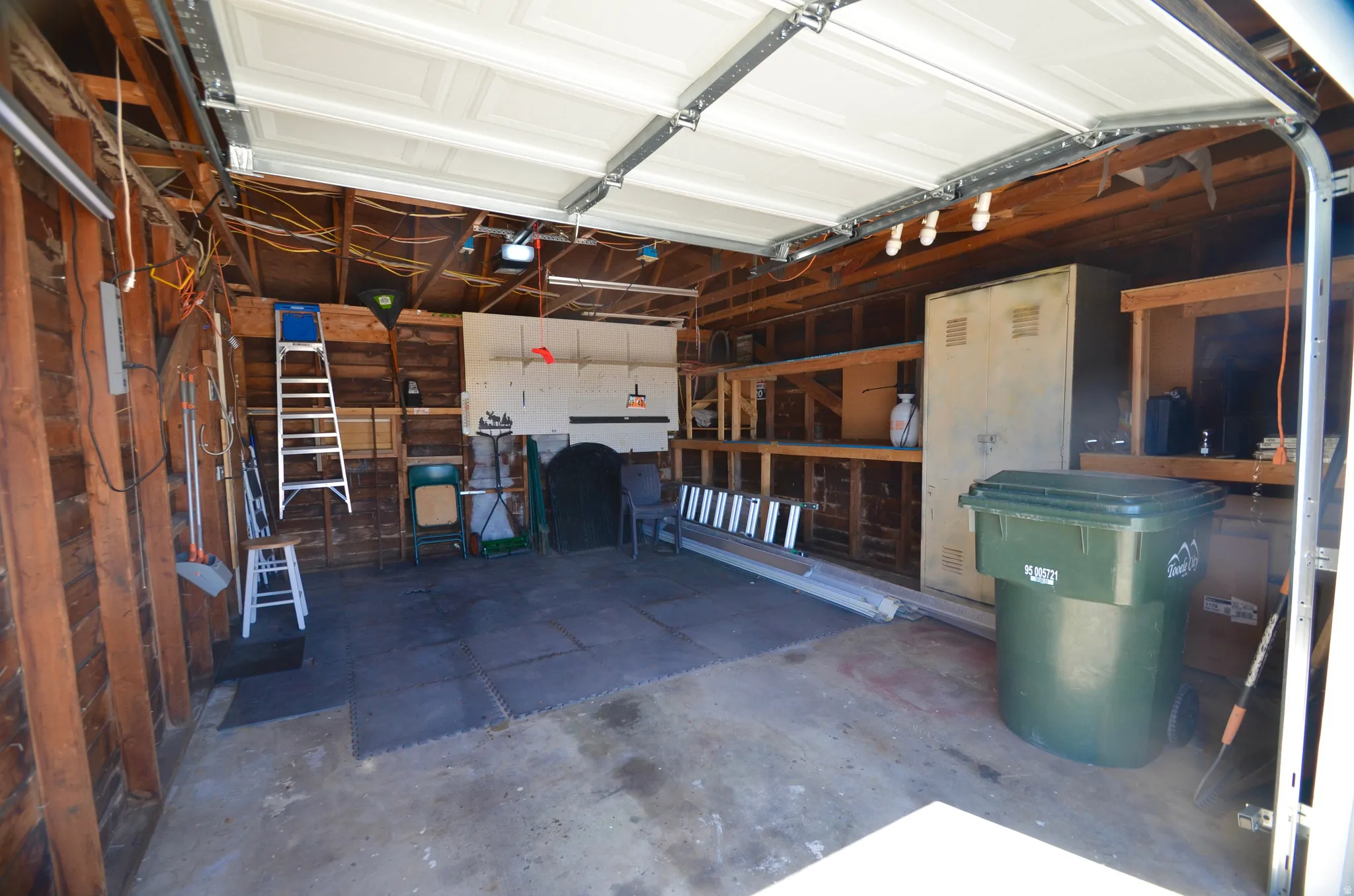 Attached garage space featuring exposed wood framing, concrete flooring, and an overhead panel garage door