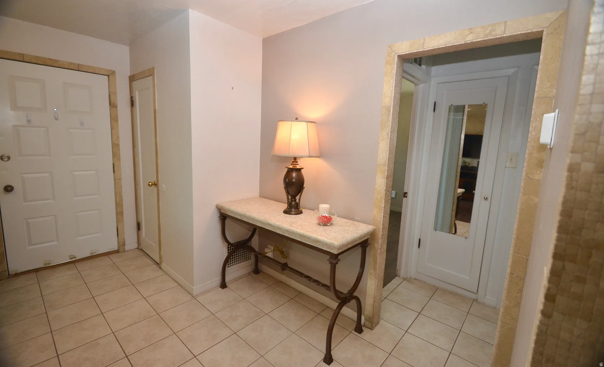 Tiled entryway featuring a white paneled door, coordinating tile flooring, and a decorative archway