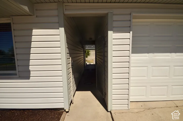 Covered breezeway entry with vinyl siding and concrete walkway