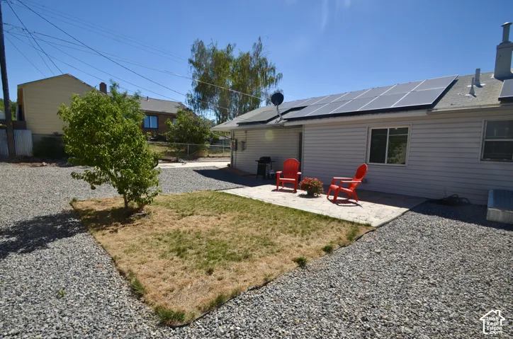 Rear exterior featuring solar panels, siding, and a concrete patio