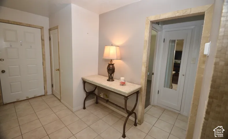 Tiled entryway featuring a white paneled door, coordinating tile flooring, and a decorative archway