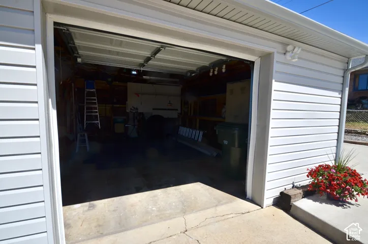 Attached garage featuring white horizontal siding, a concrete driveway approach, and an overhead garage door
