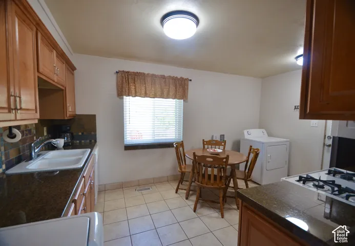 Functional kitchen featuring wood cabinetry, stone-look countertops, and a tiled backsplash