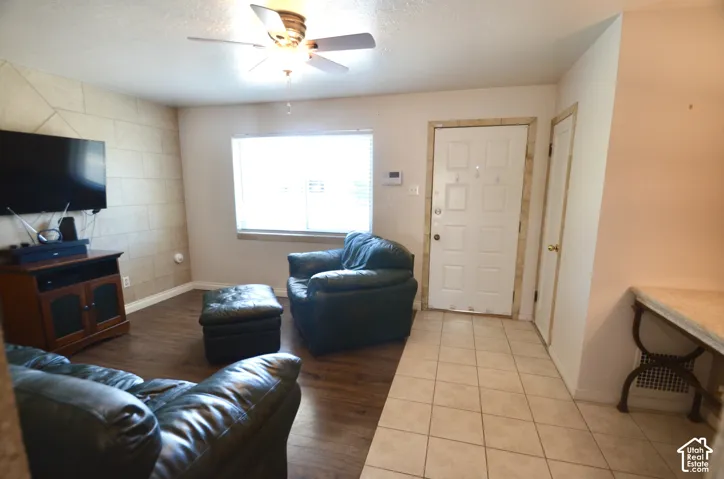 Living area featuring a prominent window, a ceiling fan with light fixture, and wood-finish flooring